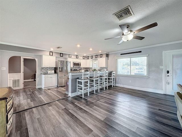 kitchen featuring a kitchen bar, white cabinetry, dark hardwood / wood-style flooring, and appliances with stainless steel finishes