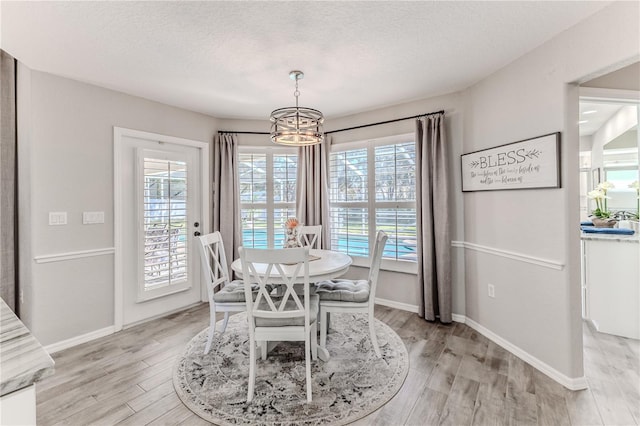 dining space featuring a notable chandelier, light hardwood / wood-style floors, and a textured ceiling