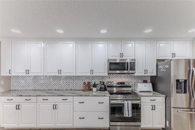 kitchen with backsplash, white cabinets, light stone countertops, a textured ceiling, and appliances with stainless steel finishes