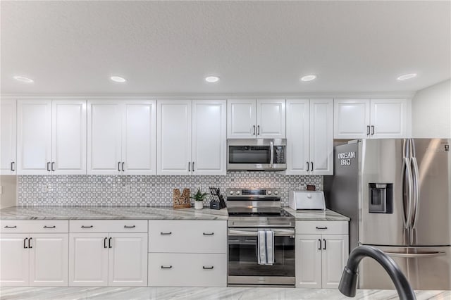 kitchen with white cabinets, light wood-type flooring, stainless steel appliances, and light stone counters