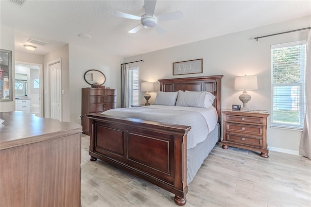 bedroom featuring connected bathroom, a closet, light hardwood / wood-style flooring, and ceiling fan