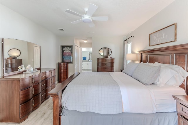 bedroom featuring ceiling fan, ensuite bathroom, and light wood-type flooring