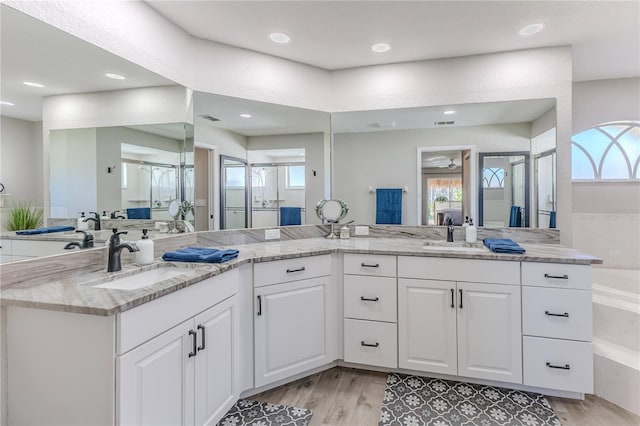 bathroom with independent shower and bath, vanity, a healthy amount of sunlight, and hardwood / wood-style flooring