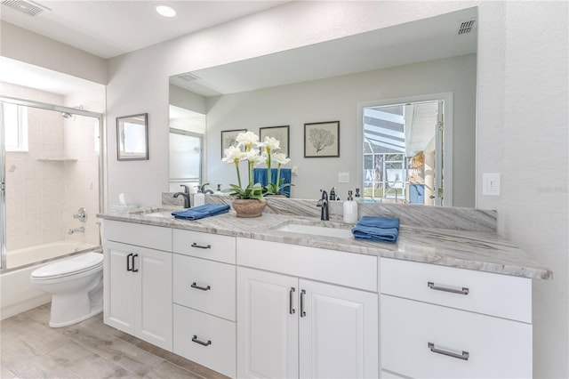 full bathroom featuring vanity, bath / shower combo with glass door, and toilet