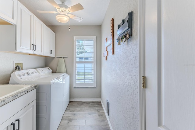 laundry area featuring cabinets, light hardwood / wood-style floors, ceiling fan, and washing machine and clothes dryer