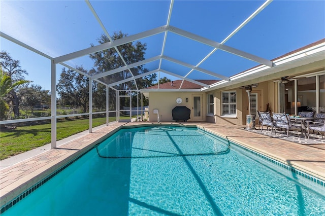 view of swimming pool with ceiling fan, a lanai, and a patio