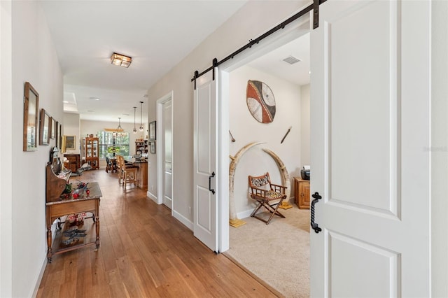 corridor with a barn door and light hardwood / wood-style flooring