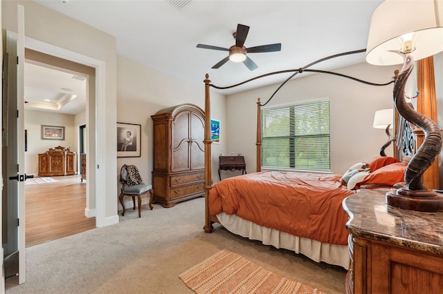 bedroom featuring ceiling fan, a raised ceiling, and light wood-type flooring