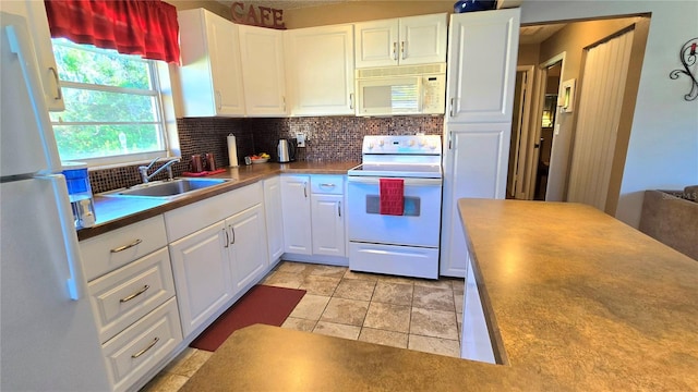 kitchen featuring light tile patterned flooring, white cabinetry, backsplash, sink, and white appliances