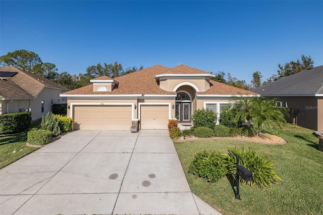 mediterranean / spanish house featuring a front yard and a garage