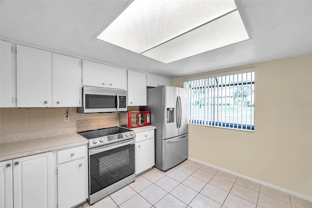 kitchen featuring white cabinets, light tile patterned floors, stainless steel appliances, and tasteful backsplash