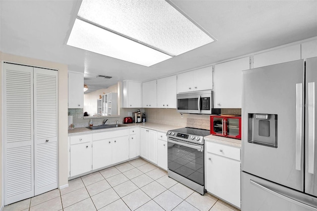 kitchen with backsplash, white cabinetry, sink, and appliances with stainless steel finishes