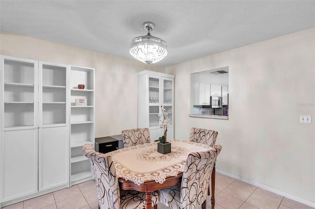 tiled dining room featuring a textured ceiling and an inviting chandelier