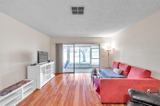 living room with light wood-type flooring and a textured ceiling