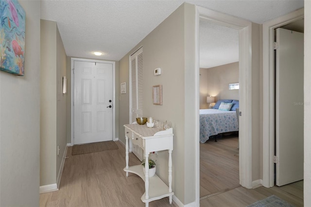 hall with a textured ceiling and light hardwood / wood-style floors