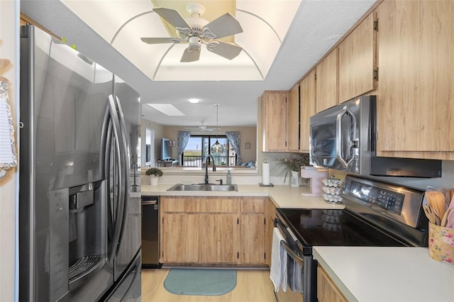 kitchen featuring ceiling fan, sink, light hardwood / wood-style floors, a tray ceiling, and appliances with stainless steel finishes