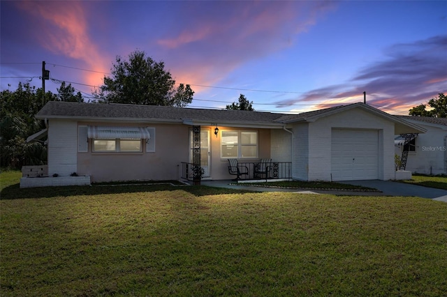 ranch-style house featuring covered porch, a lawn, and a garage