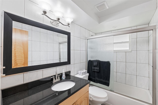 full bathroom featuring vanity, toilet, tile walls, backsplash, and bath / shower combo with glass door