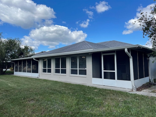 back of house with a sunroom and a lawn