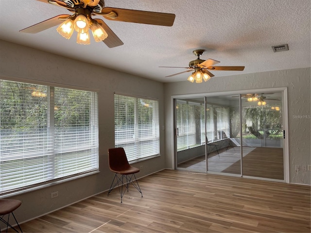 unfurnished sunroom with ceiling fan