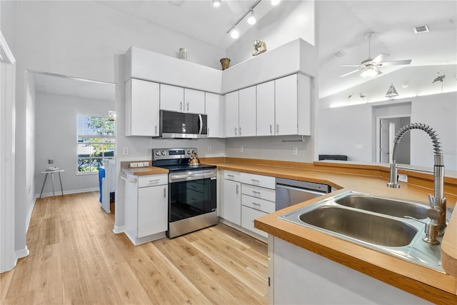 kitchen featuring white cabinetry, lofted ceiling, sink, stainless steel appliances, and light hardwood / wood-style flooring