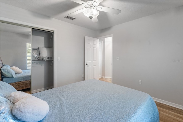 bedroom with ceiling fan, wood-type flooring, and a closet