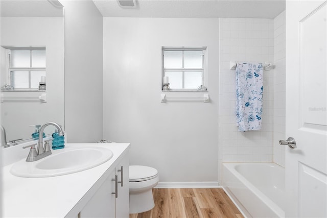 full bathroom with toilet, shower / bathing tub combination, a textured ceiling, vanity, and hardwood / wood-style floors