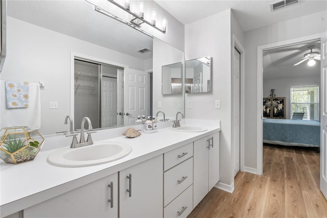 bathroom featuring vanity, ceiling fan, wood-type flooring, and a textured ceiling