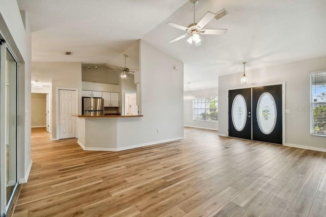 entrance foyer with ceiling fan with notable chandelier, vaulted ceiling, and light wood-type flooring