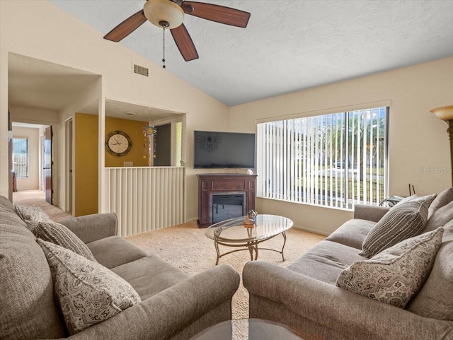 carpeted living room with ceiling fan, lofted ceiling, and a textured ceiling