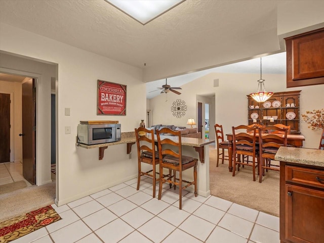 carpeted dining room with ceiling fan and a textured ceiling