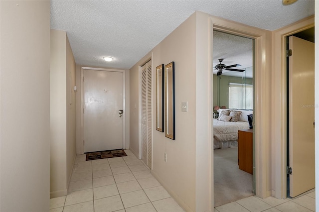 hall featuring light tile patterned floors and a textured ceiling