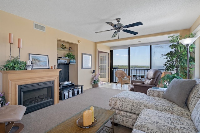 carpeted living room featuring ceiling fan and a textured ceiling