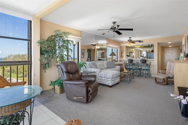 living room with ceiling fan, light tile patterned flooring, and a textured ceiling