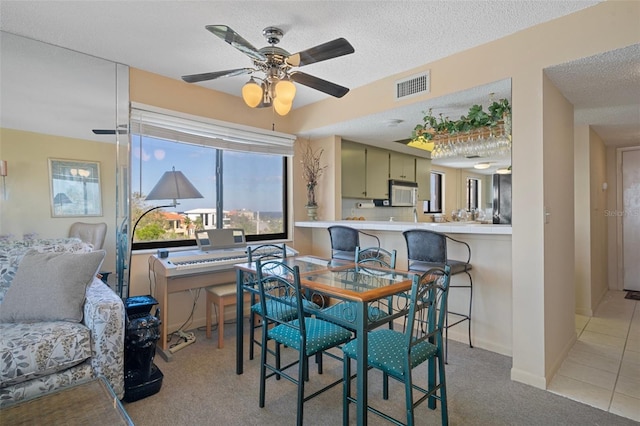 carpeted dining room with a textured ceiling and ceiling fan