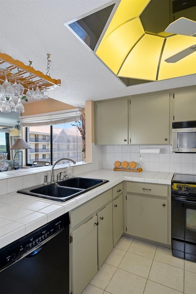 kitchen with sink, tile countertops, decorative backsplash, light tile patterned flooring, and black appliances