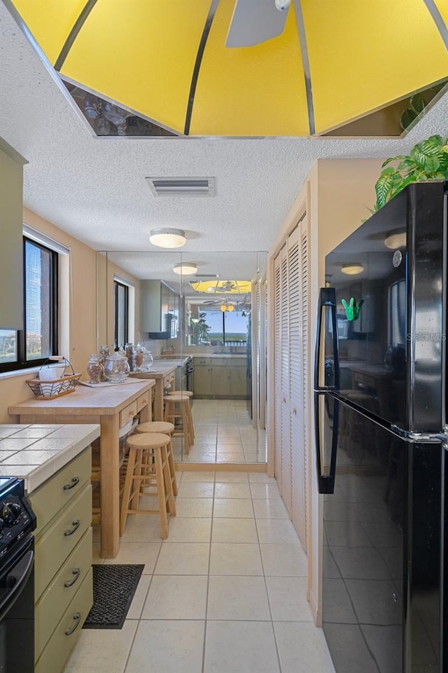 4620 Bay Blvd Unit 1148, Port Richey, FL 34668 - kitchen with black appliances, tile countertops, healthy amount of natural light, light tile patterned floors, and a textured ceiling