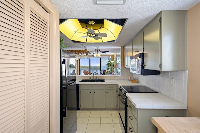 kitchen with sink, backsplash, tile countertops, light tile patterned flooring, and black appliances