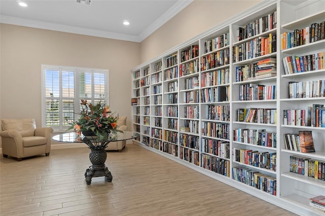 living area featuring crown molding and light hardwood / wood-style flooring