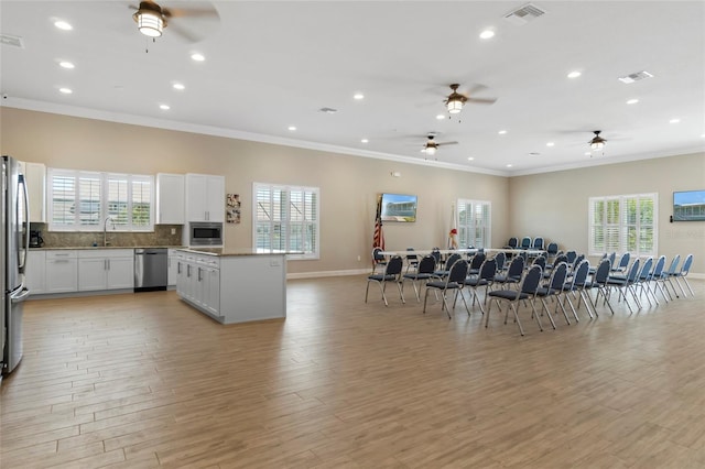 4620 Bay Blvd Unit 1148, Port Richey, FL 34668 - kitchen with appliances with stainless steel finishes, open floor plan, a ceiling fan, a kitchen island, and crown molding