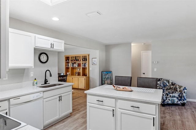 kitchen featuring dishwasher, white cabinets, sink, light hardwood / wood-style flooring, and a kitchen island