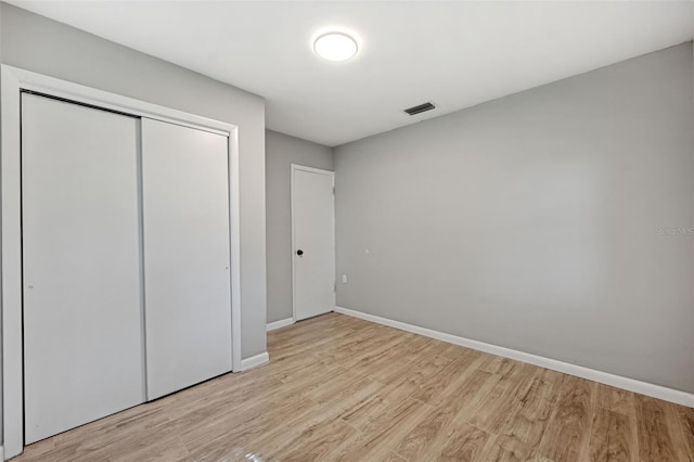 unfurnished bedroom with light wood-type flooring and a closet