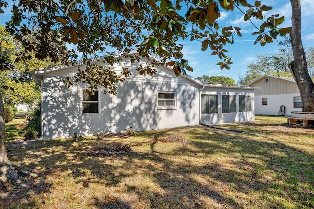 back of house featuring a lawn and a sunroom