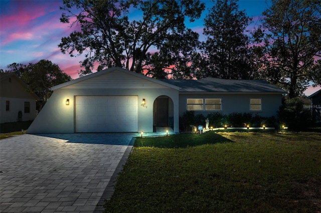 ranch-style house featuring a garage and a yard