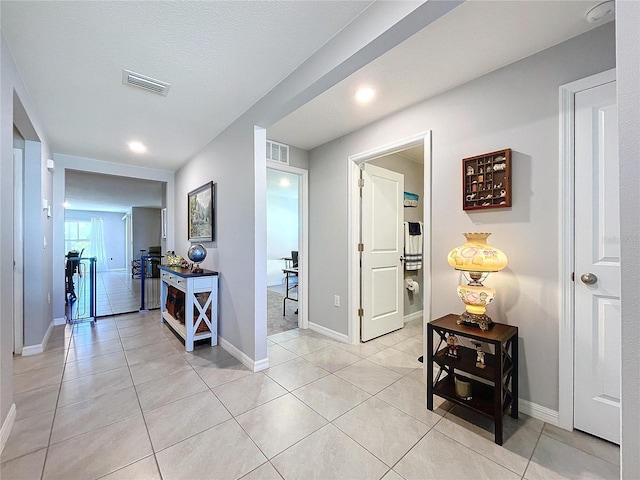 hall featuring light tile patterned floors and a textured ceiling