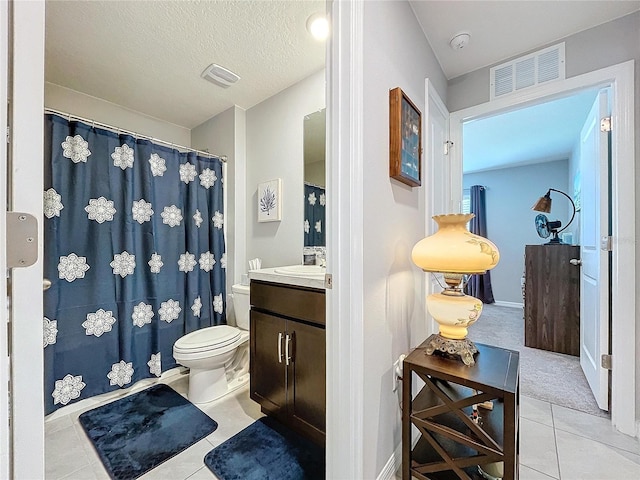 bathroom with tile patterned flooring, a textured ceiling, vanity, and toilet