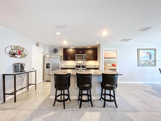 kitchen featuring sink, a kitchen bar, an island with sink, and stainless steel appliances