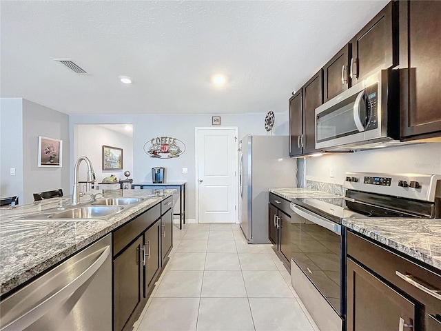 kitchen featuring light stone countertops, sink, dark brown cabinetry, and stainless steel appliances