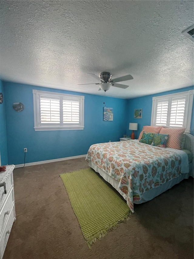 bedroom with ceiling fan, carpet floors, and a textured ceiling