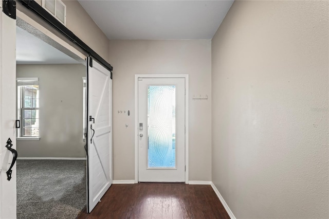 entryway with a barn door and dark wood-type flooring